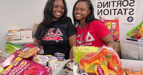 Two female students sort food items for donation.